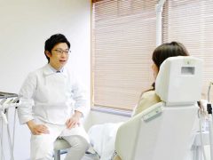 歯列矯正についてのカウンセリングを男性歯科医師から受けている女性